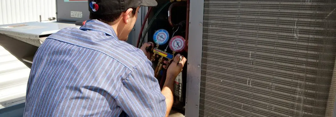 HVAC technician servicing a condenser unit in Fort Campbell North